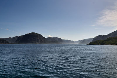 Scenic view of sea and mountains against blue sky