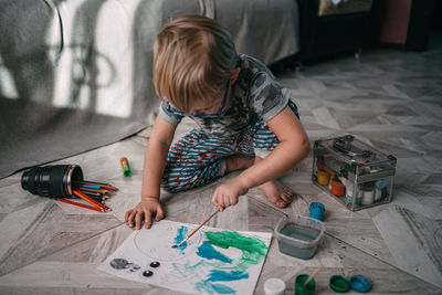 Side view of boy painting on floor