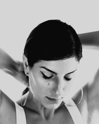 Close-up of woman tying hair against white background