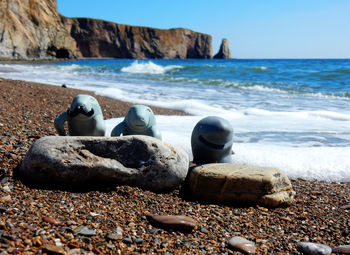 Rocks on shore at beach against sky