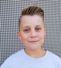 Close-up portrait of boy smiling against wall