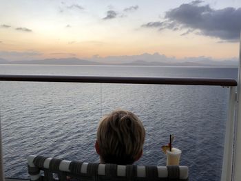 Rear view of man looking at sea against sky