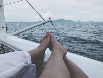 Low section of couple in boat sailing on sea