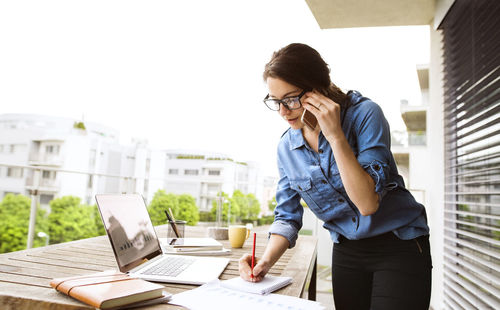 Woman on the phone working on balcony at home