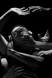 Cropped hands covering woman face over black background