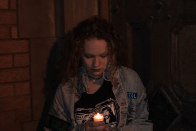 Woman holding tea light candle at night