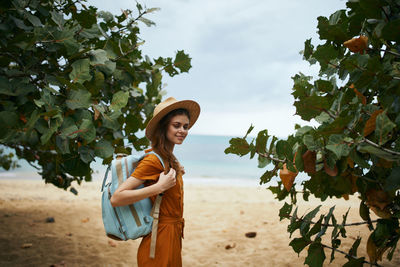 Young woman standing against tree