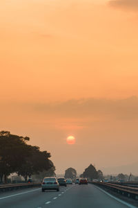 Cars on road against sky during sunset