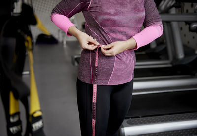 Midsection of woman standing by pink umbrella