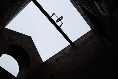 Low angle view of cross on wall against clear sky