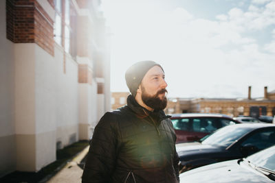Young bearded man looking away in city