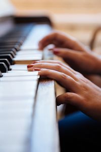 Cropped hands of woman playing piano