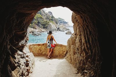 Woman standing by retaining wall by sea