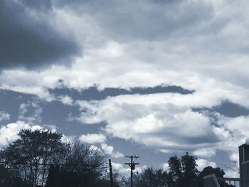 Low angle view of trees against cloudy sky