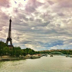 View of city at waterfront against cloudy sky