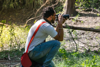 Side view of man photographing on field