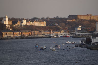 Boats on sea by buildings in city against sky