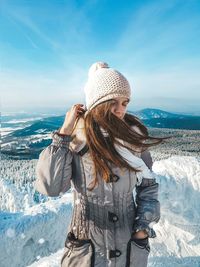 Woman wearing hat against mountain range during winter