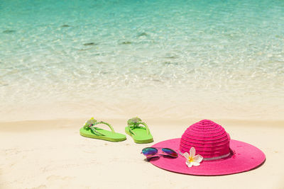 Flip-flops and straw hat on sand at beach