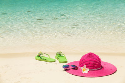 Flip flops and sun hat on sand at beach