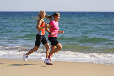 Young women running on beach, algarve, portugal