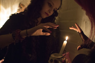 Young woman standing by candle at home