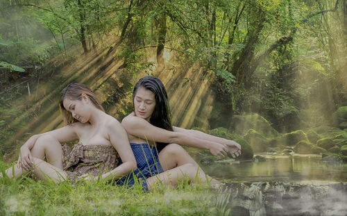 Portrait of young woman sitting by plants in lake