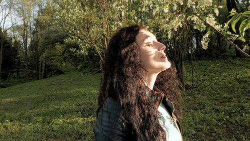 Beautiful woman sitting on tree trunk in park