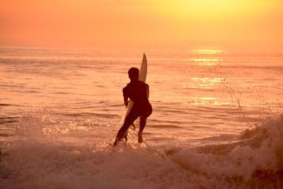 Silhouette of people on beach at sunset