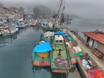Fishing boats moored at harbor on foggy day