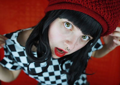 Close-up portrait of young woman sitting against red wall