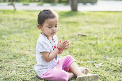 Side view of cute girl sitting on field