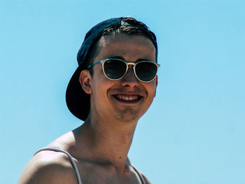 Portrait of young man wearing sunglasses against blue sky