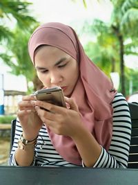 Woman in headscarf using mobile phone outdoors