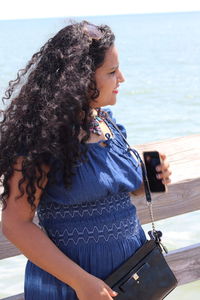 Young woman using mobile phone at sea