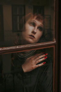 Portrait of woman looking through window