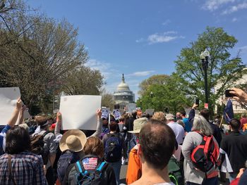 Rear view of crowd protesting at capitol building against sky