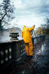 Rear view of man cleaning statues with high pressure cleaner 