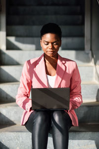 Businesswoman using laptop while sitting on staircase