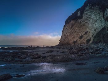 Rock formation on beach against sky