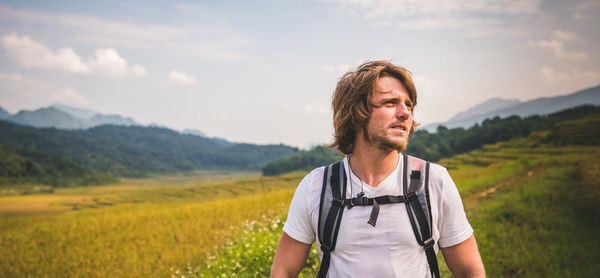 Young man standing on field against sky