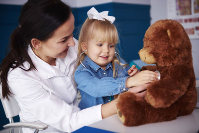 Doctor and girl examining teddy in medical practice