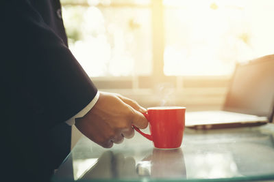 Man holding coffee cup on table