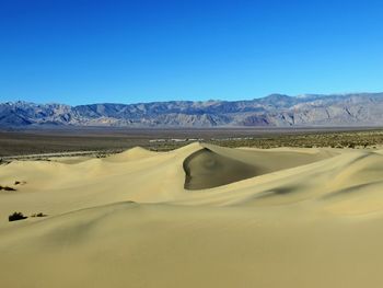 Scenic view of desert against clear blue sky