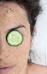 Close-up of woman with facial mask and cucumber 