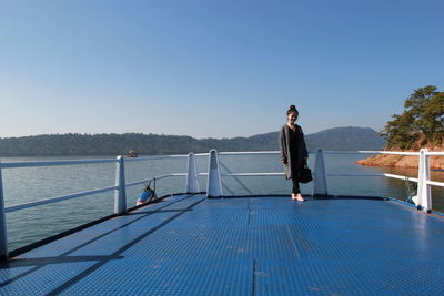 Man standing by swimming pool against clear blue sky