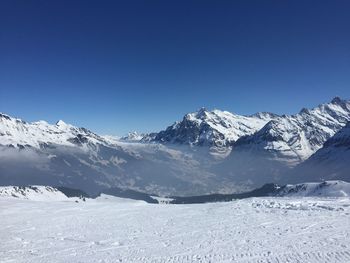 Scenic view of snow covered mountains against clear blue sky