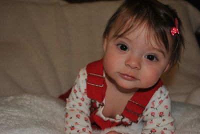 Close-up portrait of cute baby girl lying on bed