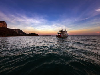 Boat sailing in sea against sky during sunset
