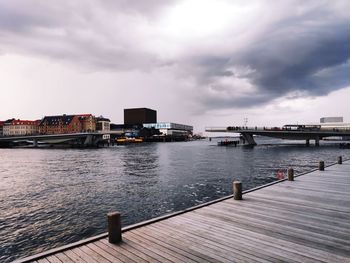 Pier over river in city against sky